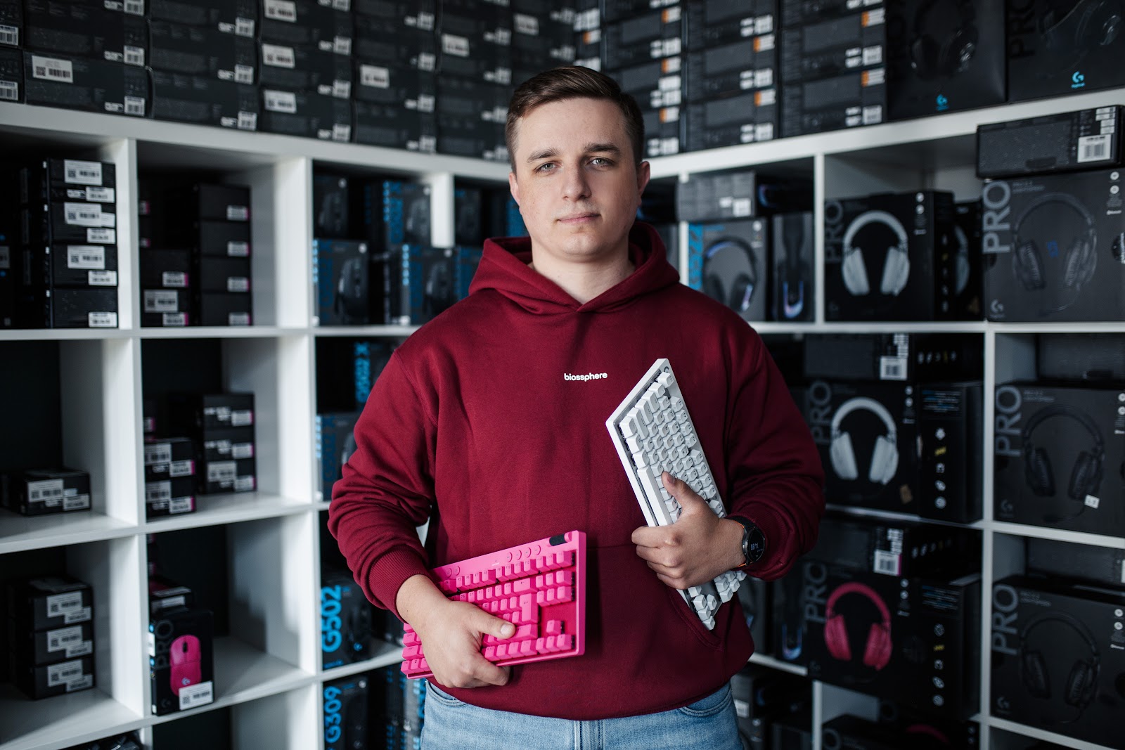 Inside the peripheral preparation area - keyboards staged for pairing and testing in front of the Logitech G peripheral shelves.
